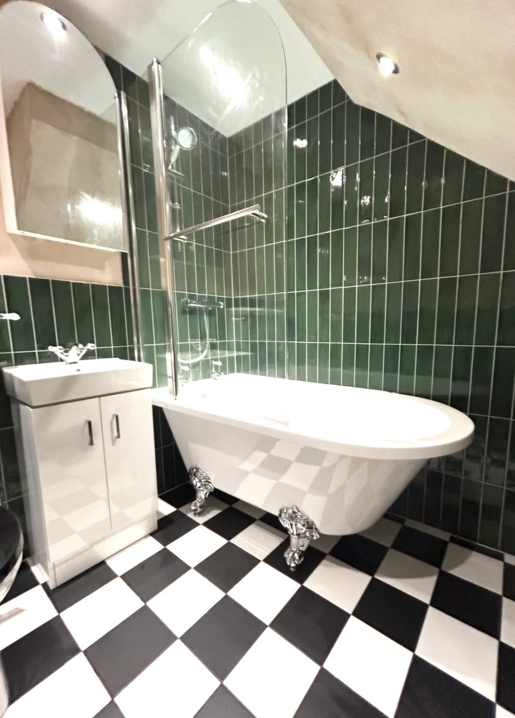 Green vertical metro tiled bathroom with roll top bath and black and white chequerboard floor
