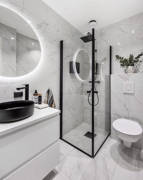 Compact marble effect en-suite with black framed corner shower enclosure and black counter top basin