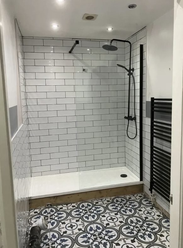 Large walk-in shower tray fitted where a bath was removed, with white metro tiled walls
