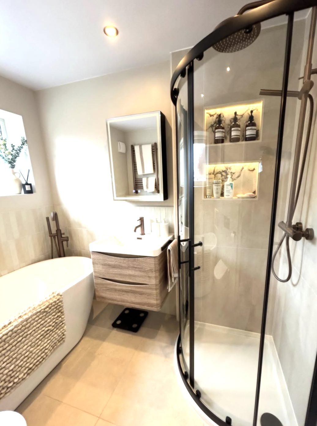 Warm neutral bathroom with freestanding bath, curved shower enclosure and wall hung vanity