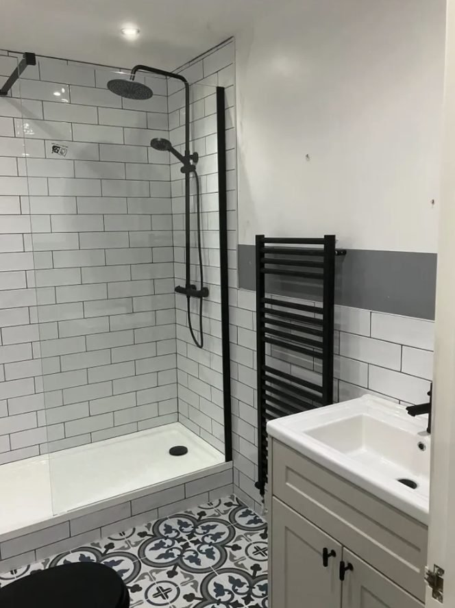 Shower room with white metro tiles, dark grout, black heated towel rail and patterned floor tiles